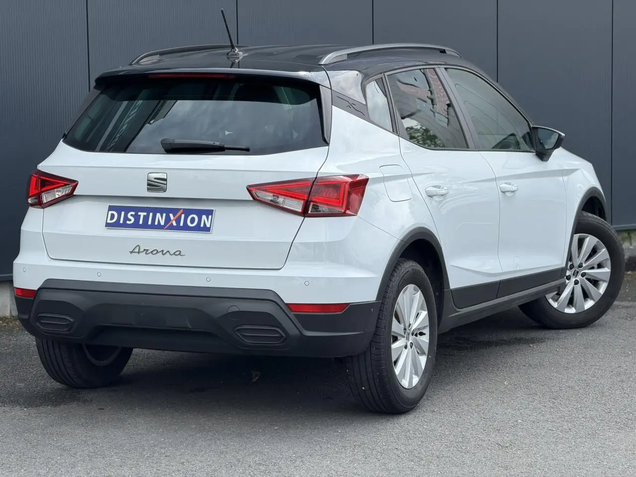 Vue 3/4 arrière droite d'un SEAT Arona blanc alpin avec toit noir et jantes alliage 16 pouces.