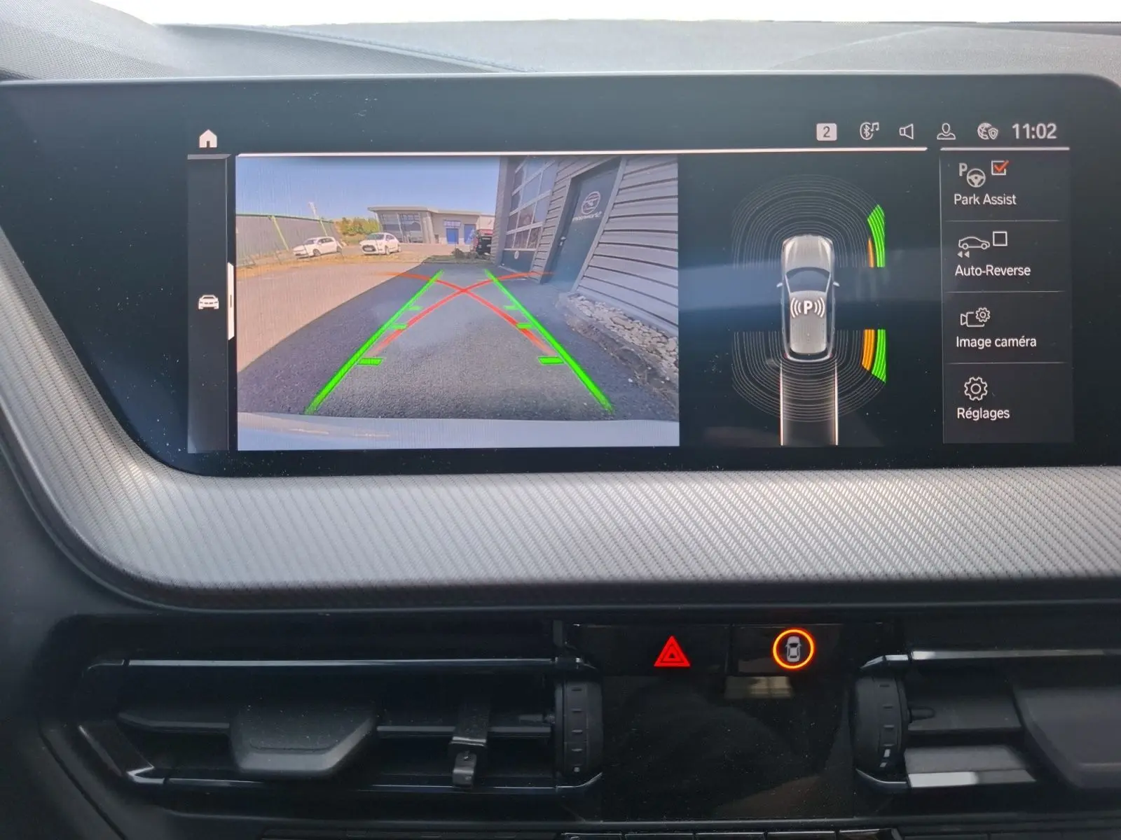 Écran de caméra de recul et radar de stationnement actif dans le tableau de bord d'une BMW Série 1 blanche.