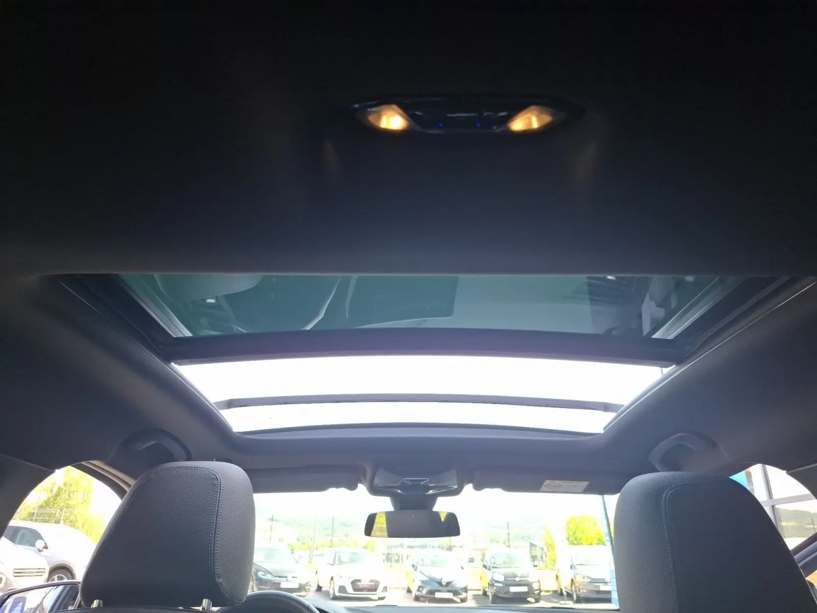 Vue intérieure du toit ouvrant panoramique de la BMW Série 1 118D M Sport blanche avec sièges avant visibles.