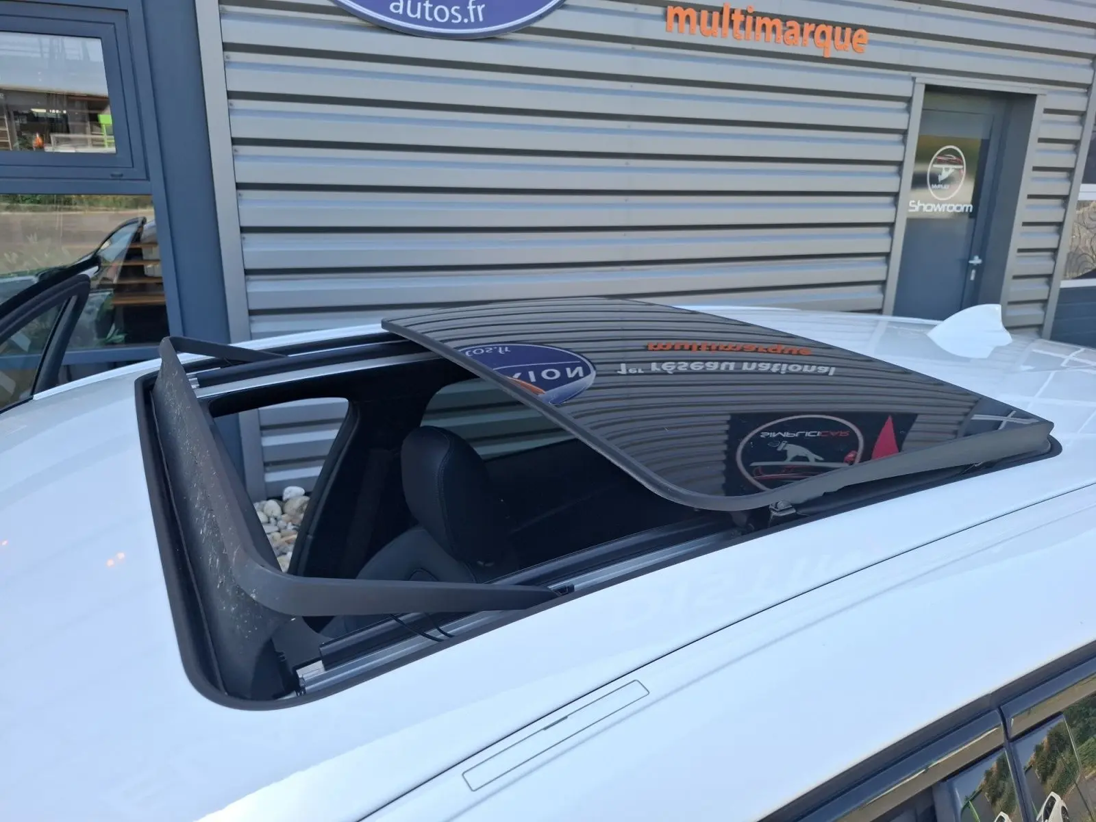 Toit ouvrant panoramique ouvert sur une BMW Série 1 118D M Sport blanc vue de dessus côté gauche.