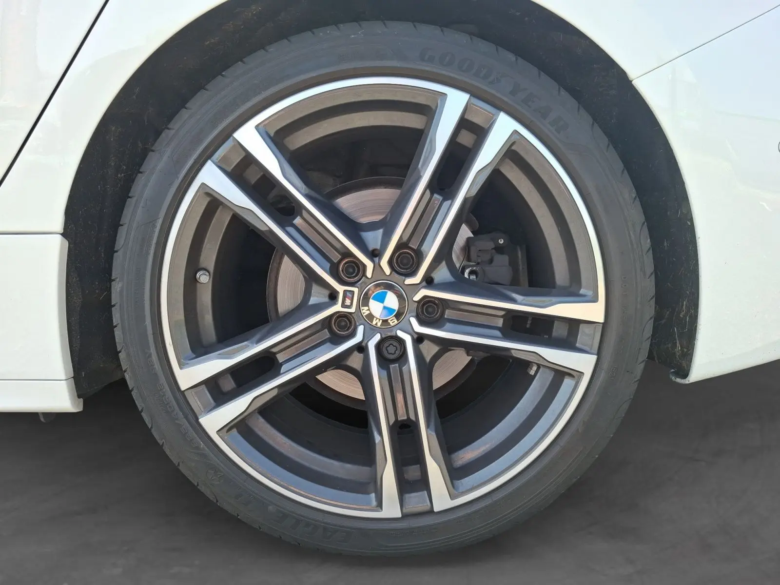 Gros plan sur la jante alliage 18 pouces M Sport noire et argentée de la BMW Série 1 blanche côté arrière droit.