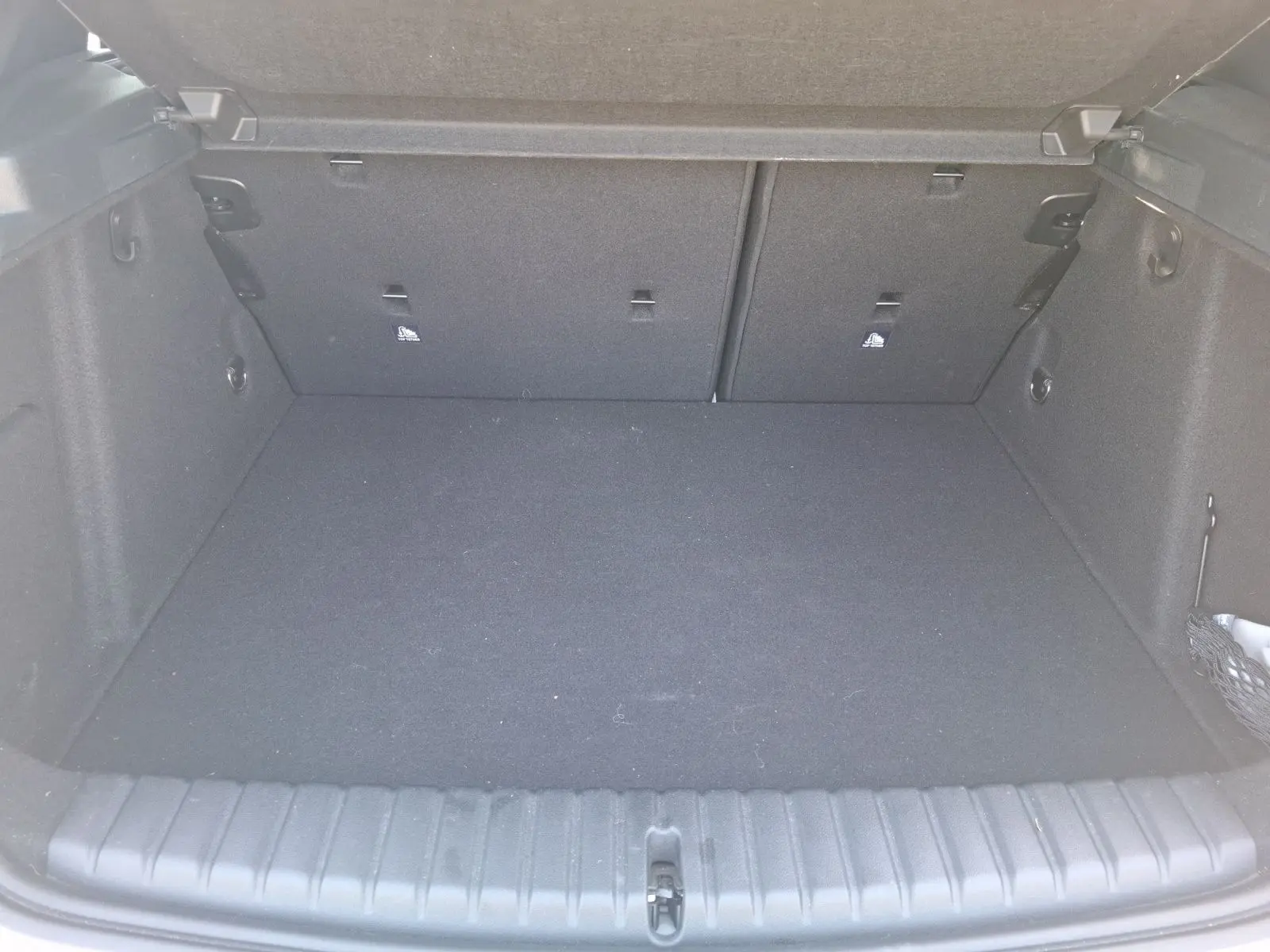 Coffre vide en vue plongeante d'une BMW Série 1 118D M Sport blanche, montrant l'espace de chargement et les fixations Isofix.