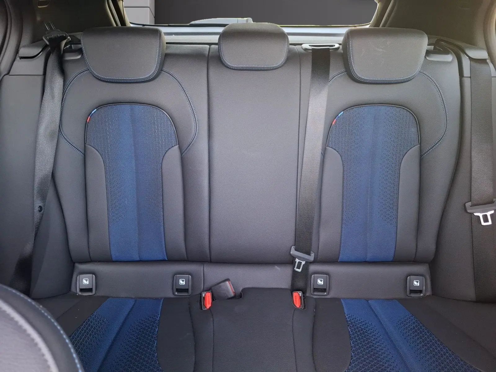 Vue intérieure des sièges arrière baquets en cuir et tissu bleu et noir de la BMW Série 1 118D M Sport 2021.
