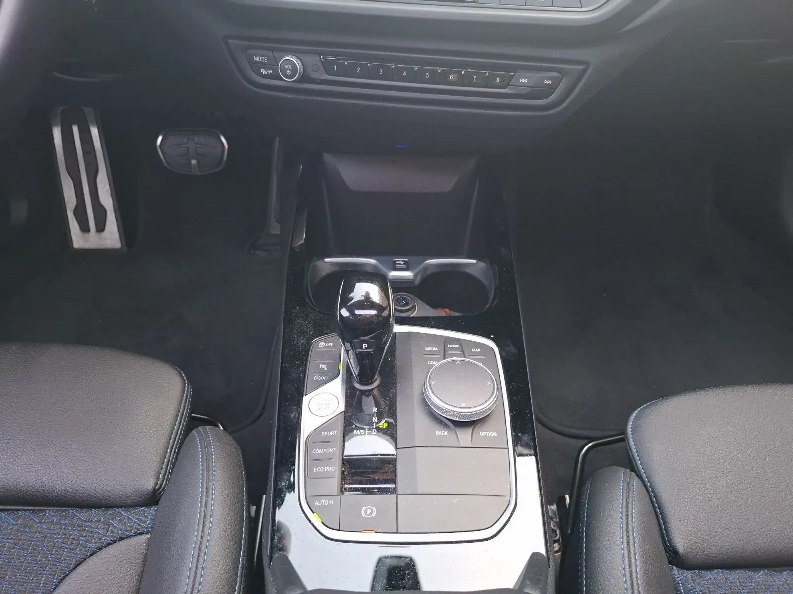 Vue plongeante sur la console centrale de la BMW Série 1 118D M Sport blanche, avec levier de vitesse et commandes multimédia.