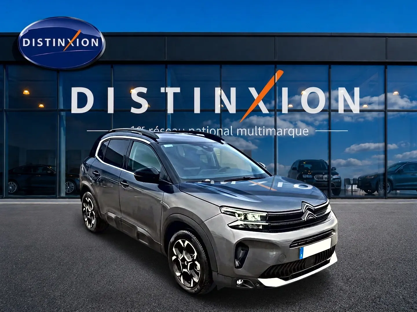 Citroën C5 Aircross gris vue 3/4 avant droit, avec jantes alu et barres de toit devant showroom Distinxion.