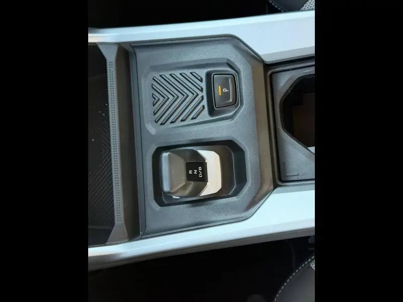 Vue rapprochée de la console centrale grise Schiste du Dacia Bigster 2025, avec sélecteur de boîte auto et bouton de frein à main électrique.