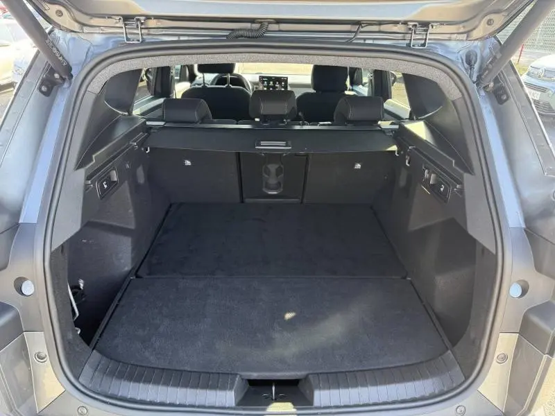 Coffre ouvert vu de l'arrière du Dacia Bigster gris schiste, montrant l'espace de chargement et la banquette arrière.