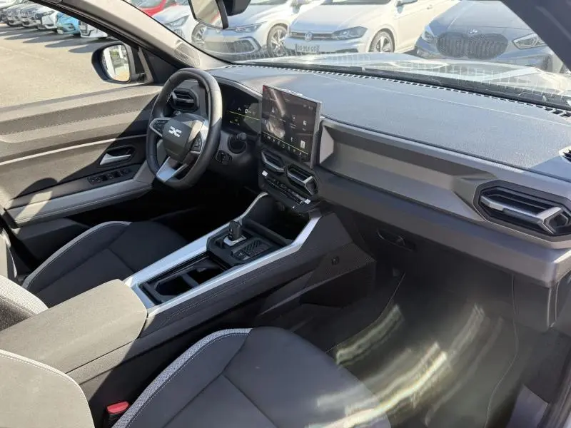 Vue intérieure côté conducteur du Dacia Bigster gris schiste 2025, avec tableau de bord moderne et écran tactile central.
