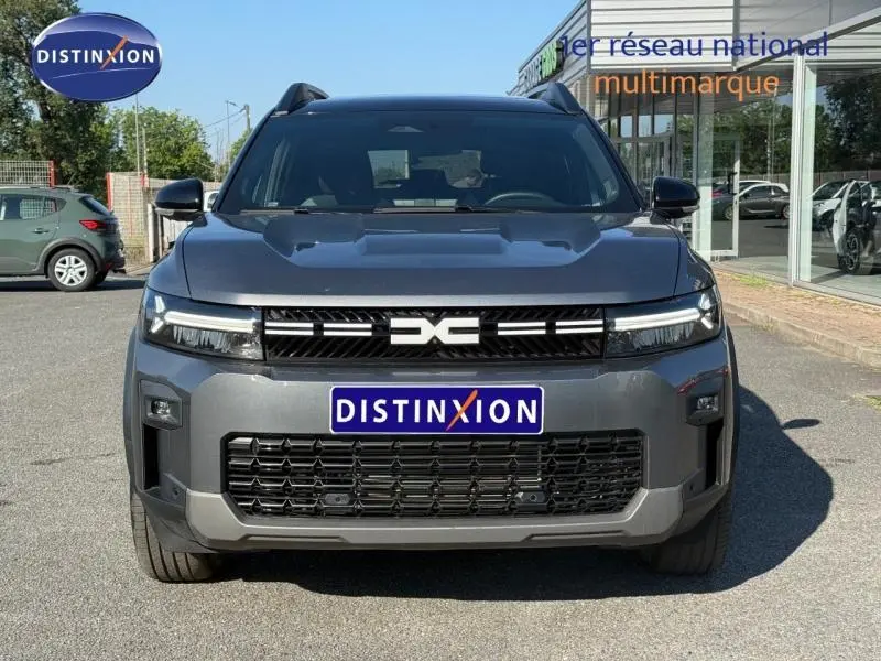 Vue de face du Dacia Bigster gris schiste 2025 avec calandre noire et logo distinctif central sur parking.