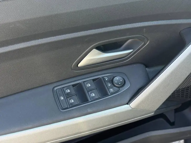 Vue rapprochée de la porte avant gauche grise du Dacia Bigster avec commandes électriques des vitres et poignée argentée.