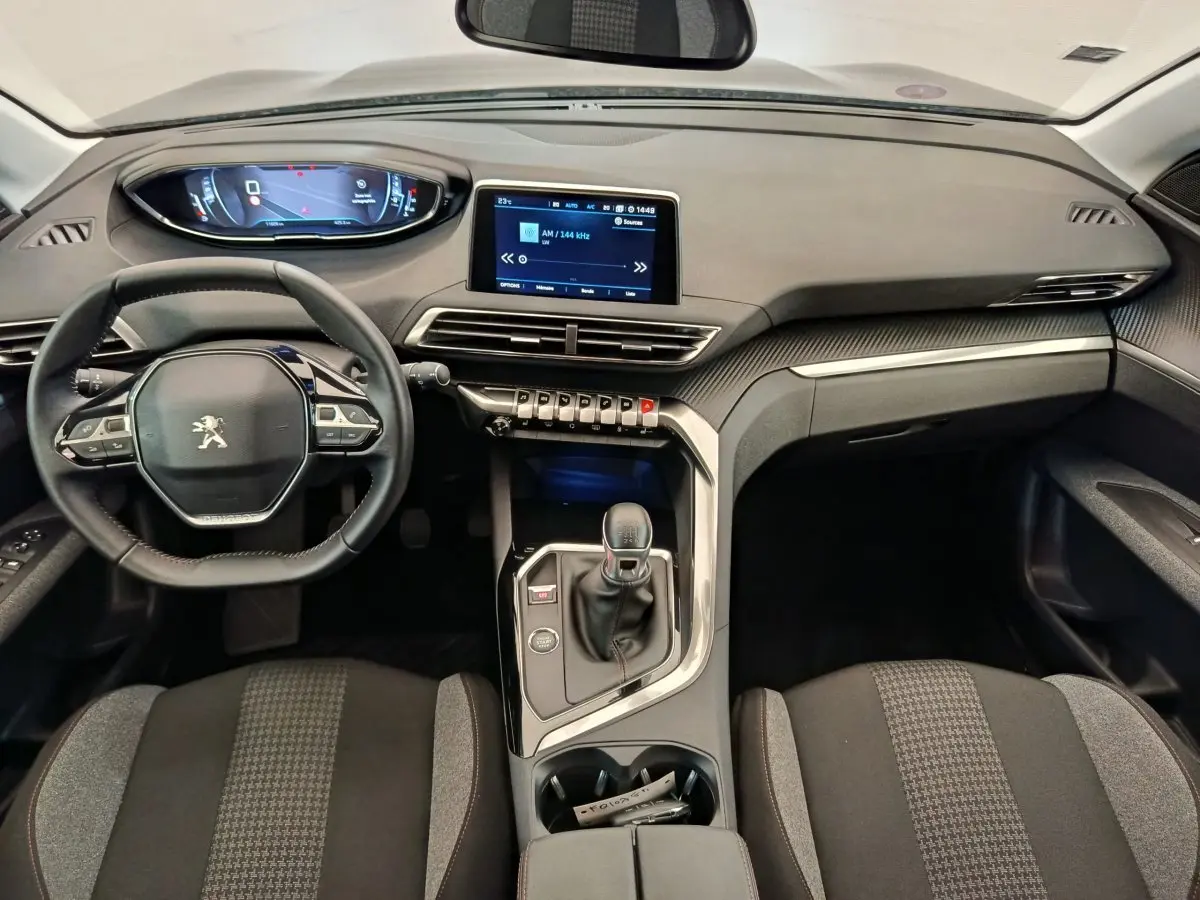 Vue intérieure frontale du tableau de bord et volant cuir du Peugeot 3008 gris foncé avec écran tactile central.