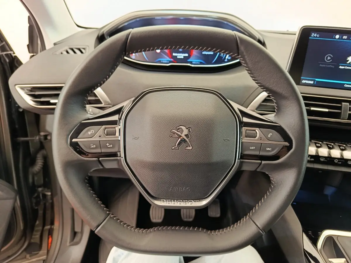 Vue rapprochée du volant cuir multifonctions du Peugeot 3008 gris foncé, avec tableau de bord digital et écran tactile visible.