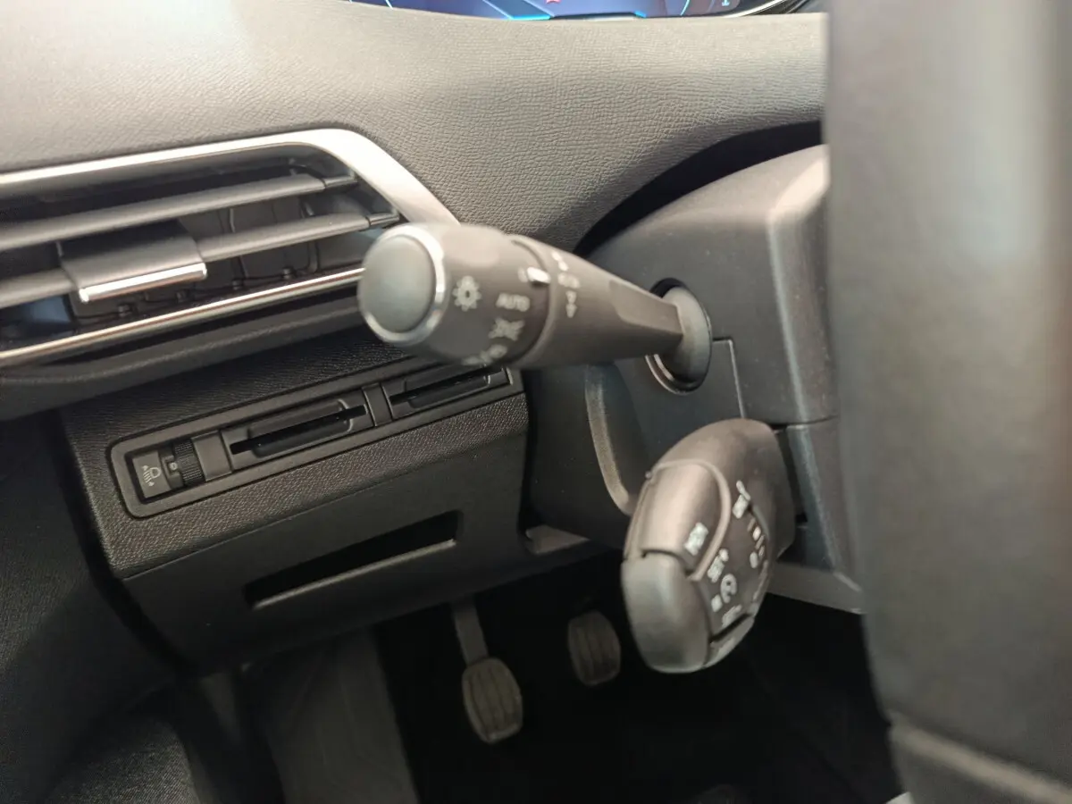 Gros plan sur les commandes de phares et essuie-glaces à gauche du volant du Peugeot 3008 gris foncé, version 2020.