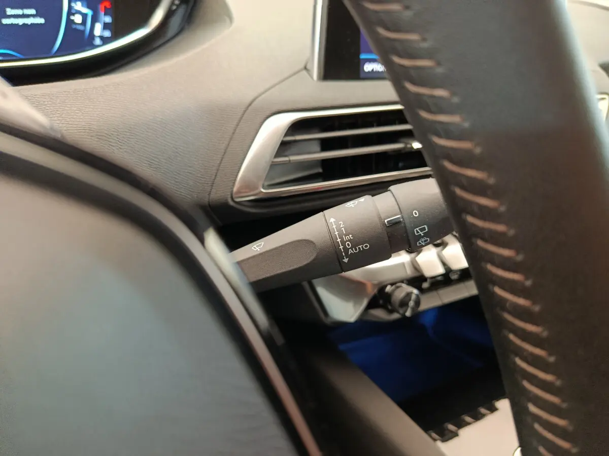 Gros plan sur la manette d'essuie-glace à gauche du volant cuir dans l'habitacle gris foncé du Peugeot 3008 2020.