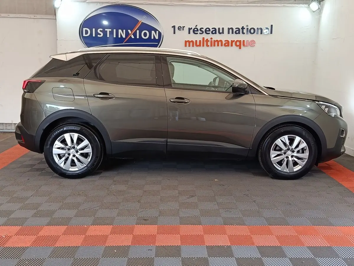 Vue latérale droite d'un Peugeot 3008 gris foncé, version Puretech 130 S&S Active Business, en intérieur showroom.