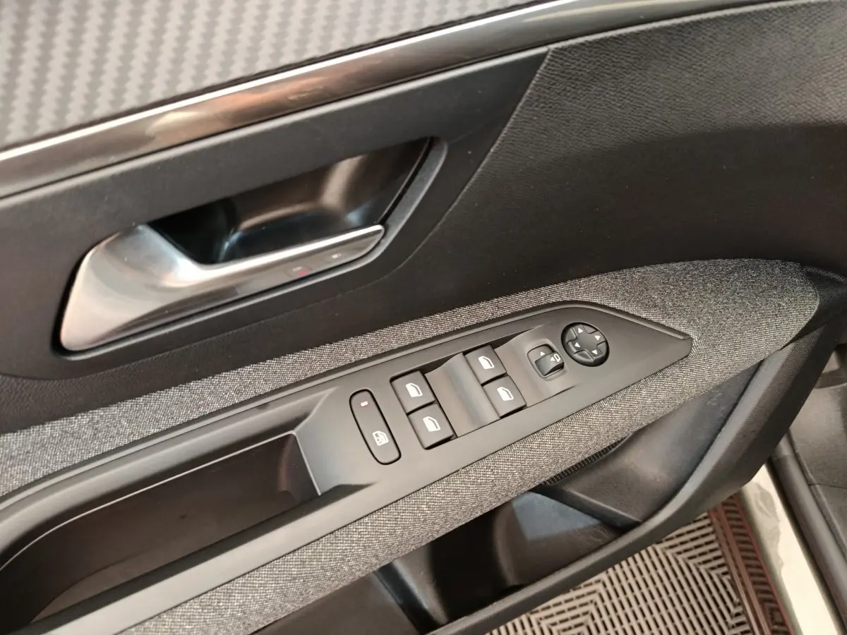Gros plan sur la porte côté conducteur du Peugeot 3008 gris foncé, montrant les commandes des vitres et le bouton de verrouillage.