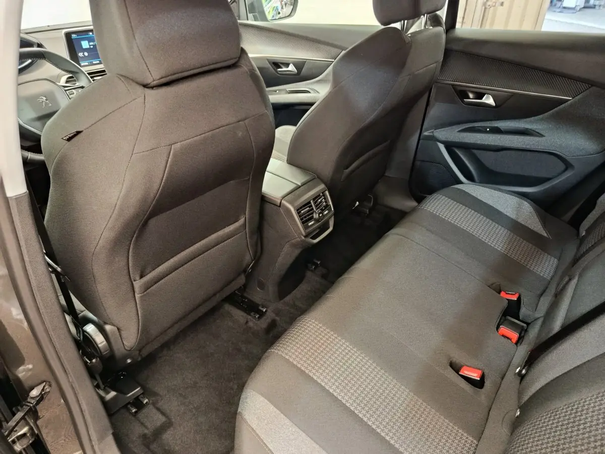 Vue arrière intérieure du Peugeot 3008 gris foncé, montrant les sièges arrière et la console centrale avec aérateurs.