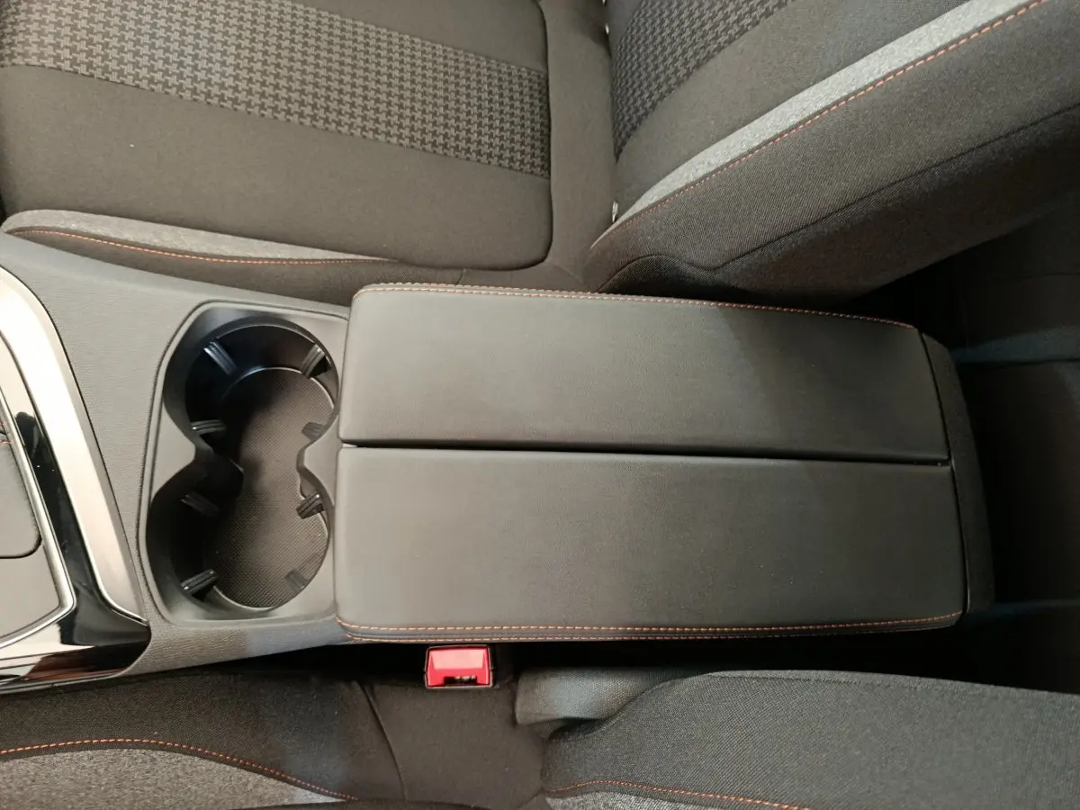 Vue rapprochée de l'accoudoir central noir avec surpiqûres orange et porte-gobelets du Peugeot 3008 gris foncé 2020.