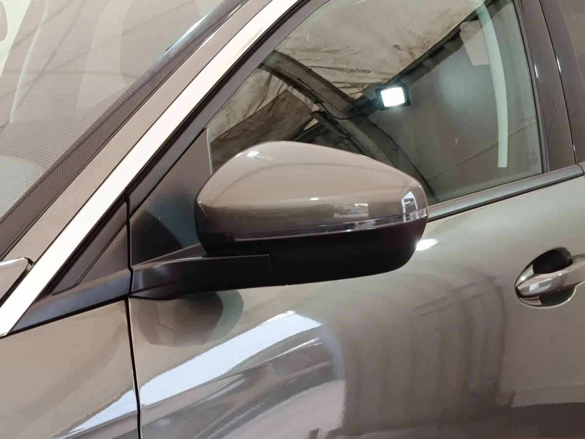 Gros plan sur le rétroviseur côté gauche d'un Peugeot 3008 gris foncé, avec reflet de lumière intérieure.