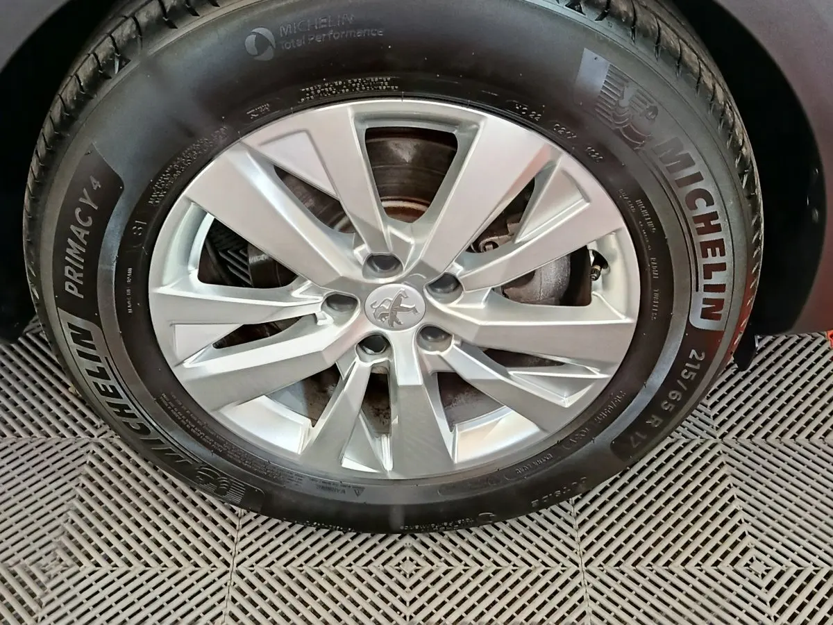 Gros plan sur la roue avant droite d’un Peugeot 3008 gris foncé avec jante alliage et pneu Michelin Primacy 4.