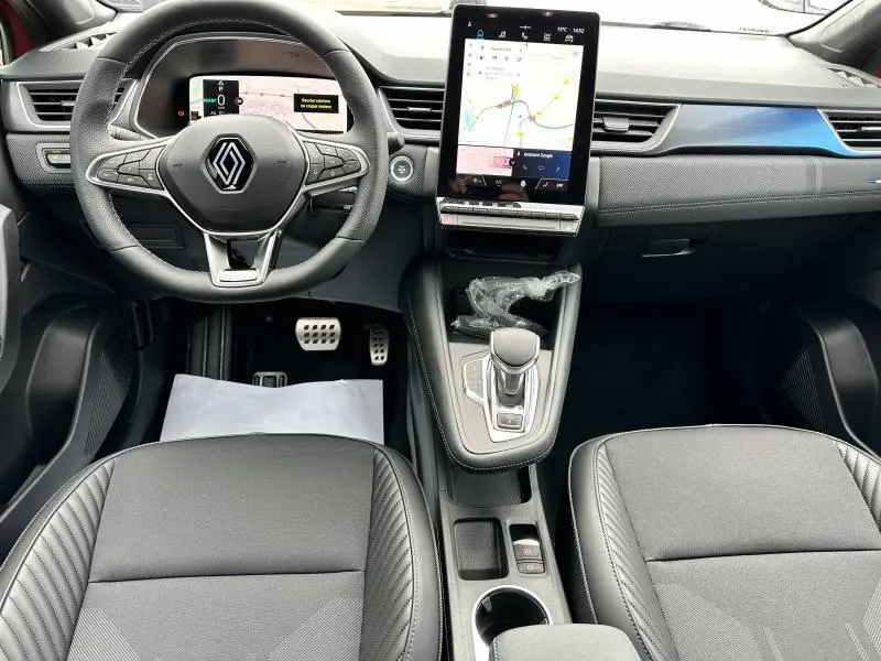 Vue intérieure avant du Renault Captur 2025 hybride, tableau de bord moderne avec écran tactile vertical et volant multifonction.