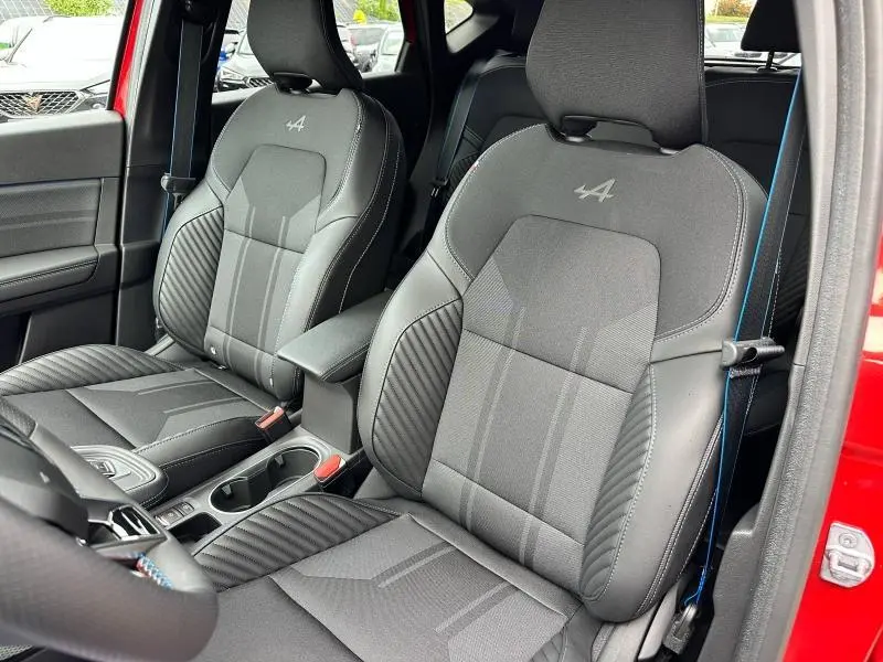 Vue intérieure côté conducteur du Renault Captur 2025, sièges noirs esprit Alpine avec logo brodé et surpiqûres bleues.