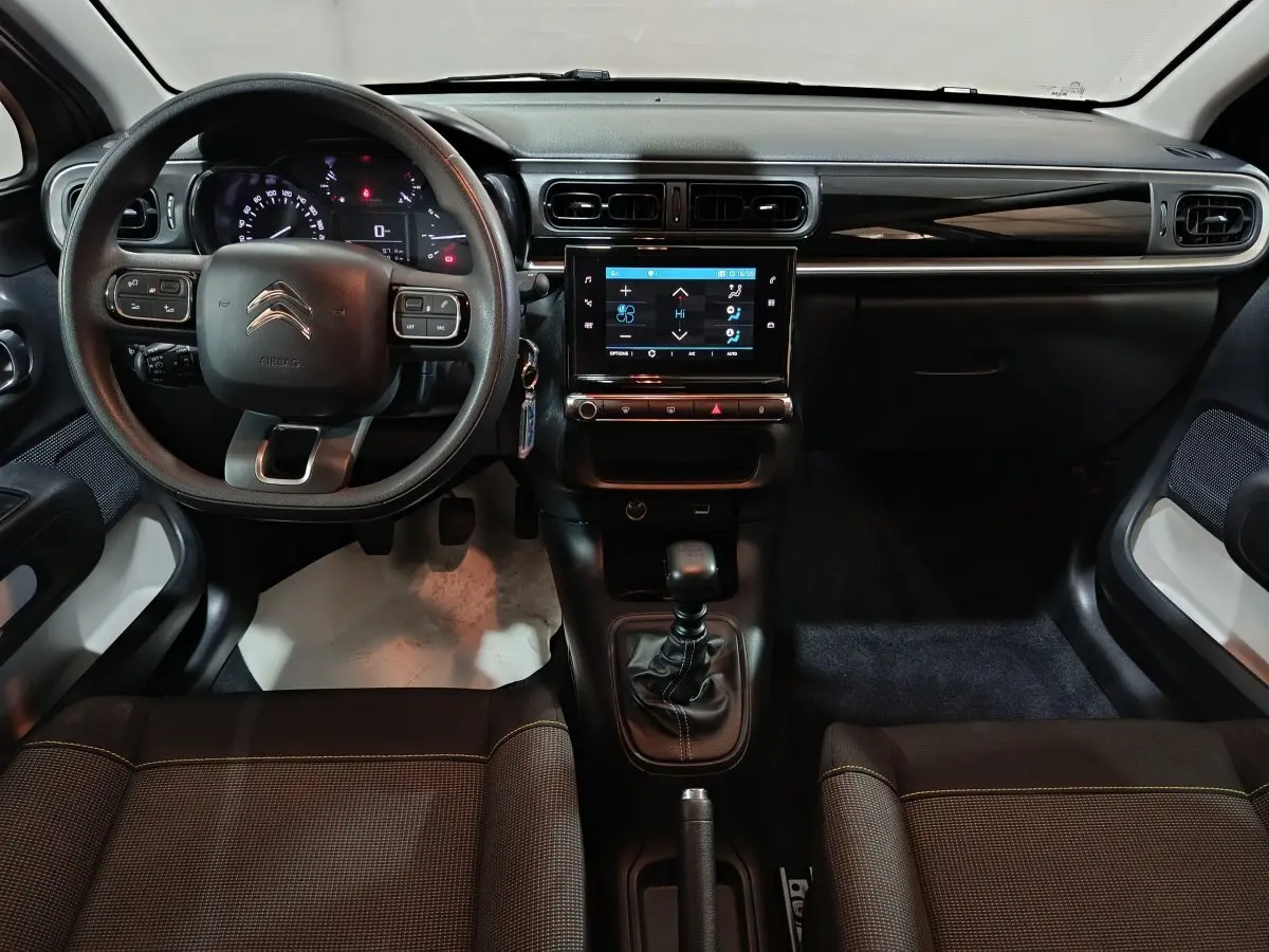 Vue intérieure avant du tableau de bord et volant noir d'une Citroën C3 2024 avec écran tactile central et boîte manuelle.