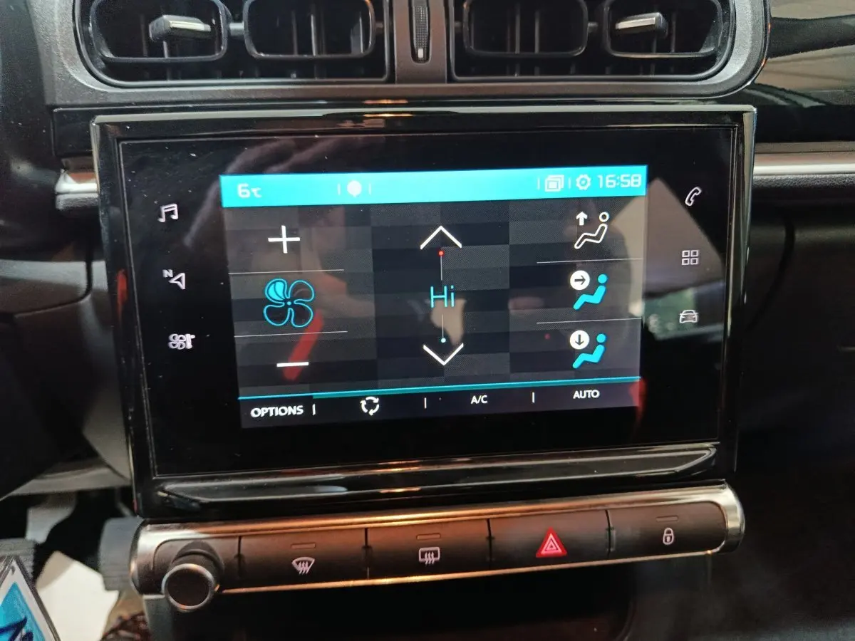 Vue rapprochée de l'écran tactile central noir affichant les commandes de climatisation dans une Citroën C3 gris foncé 2024.