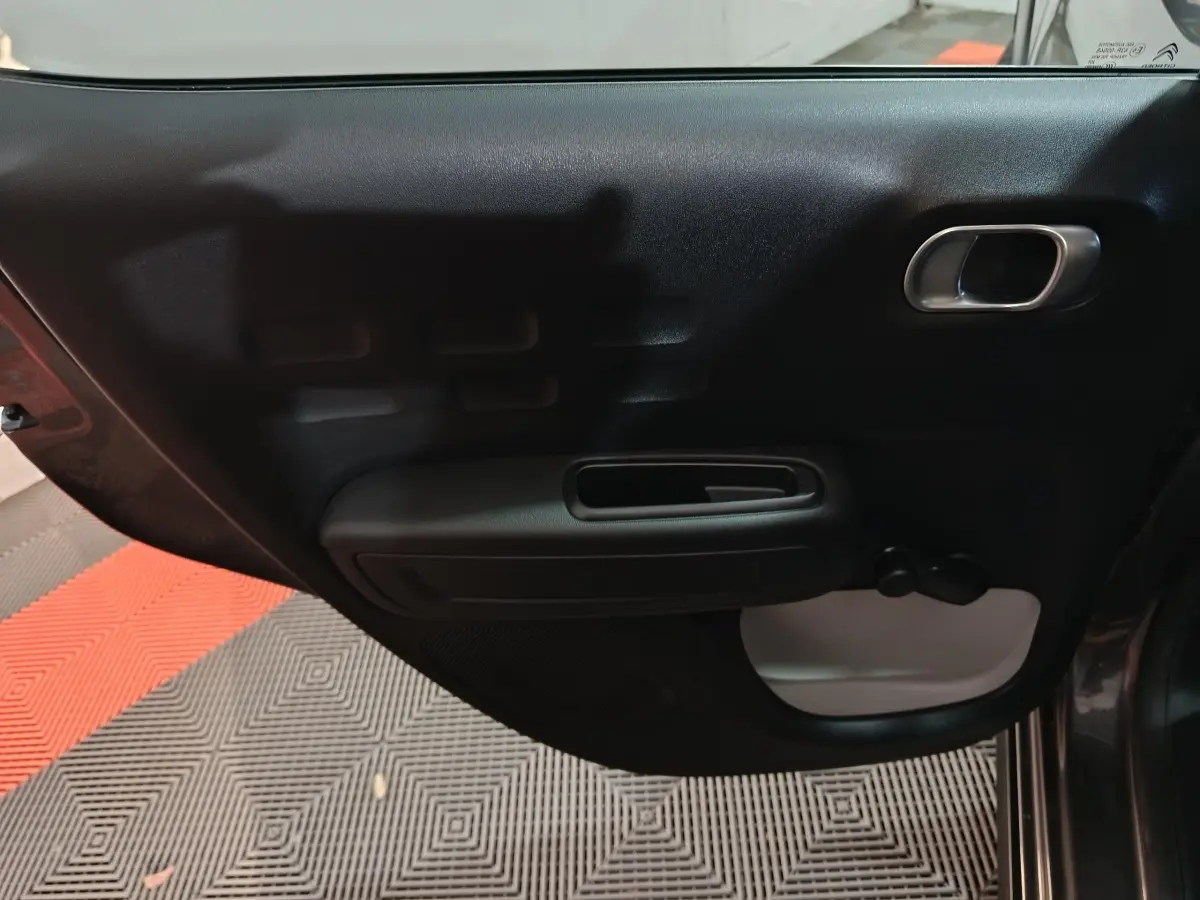 Vue côté intérieur de la porte avant droite gris foncé de la Citroën C3 avec poignée et manivelle de vitre.