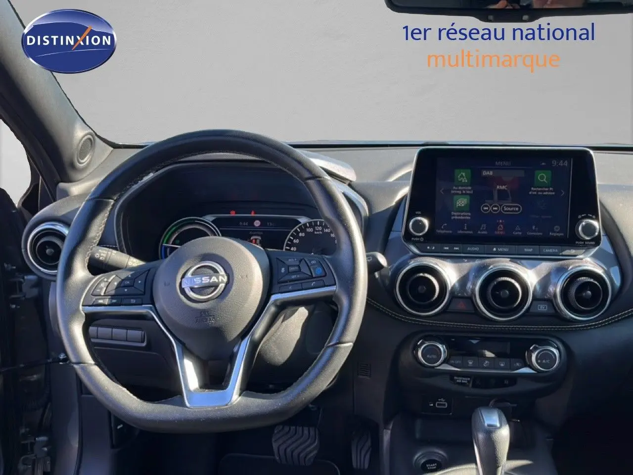 Vue intérieure du tableau de bord du Nissan Juke Hybrid 2024, avec volant cuir noir et écran tactile central.