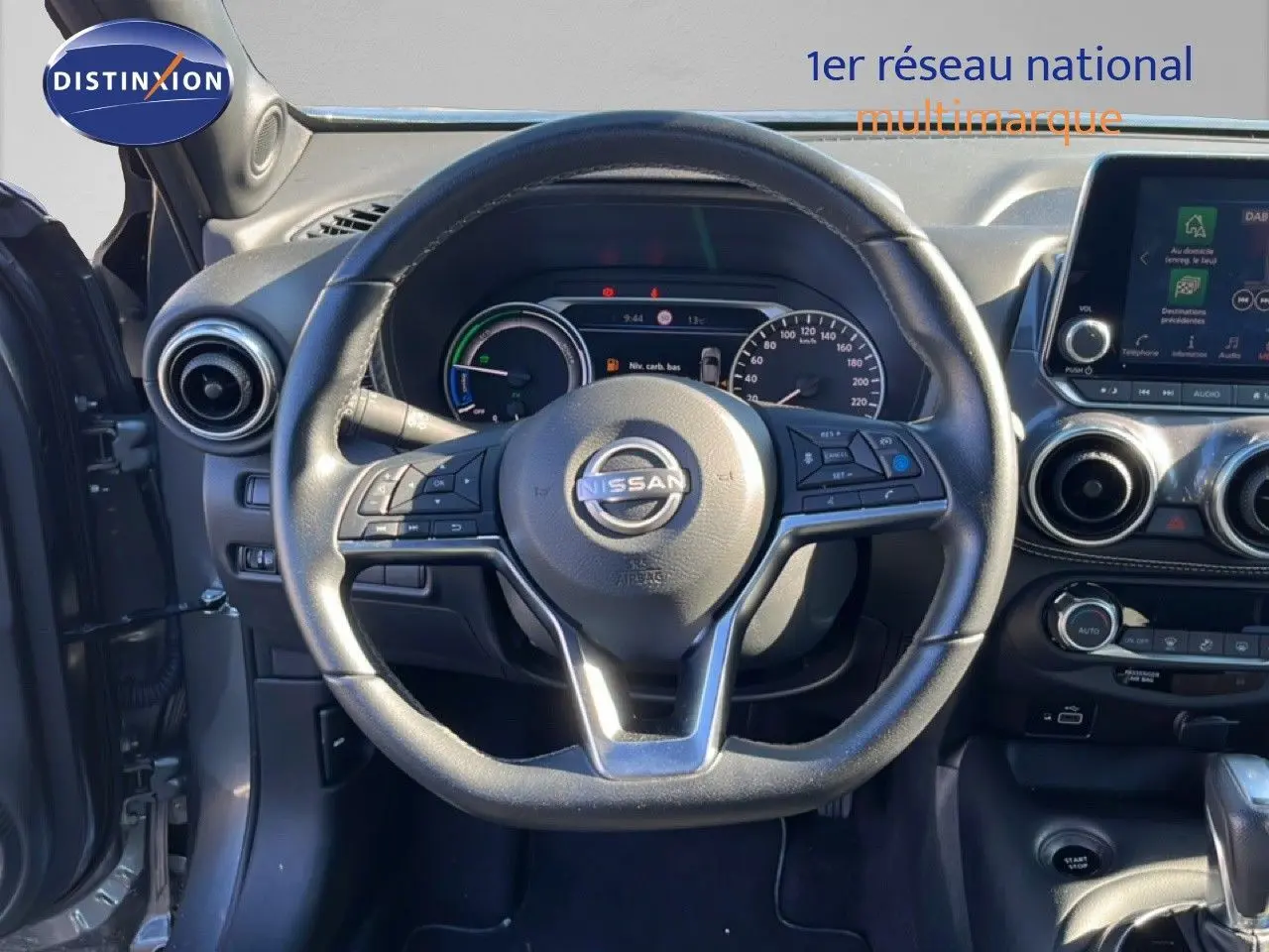 Vue intérieure centrée sur le volant Nissan Juke gris squale métal, avec tableau de bord et écran tactile visibles.