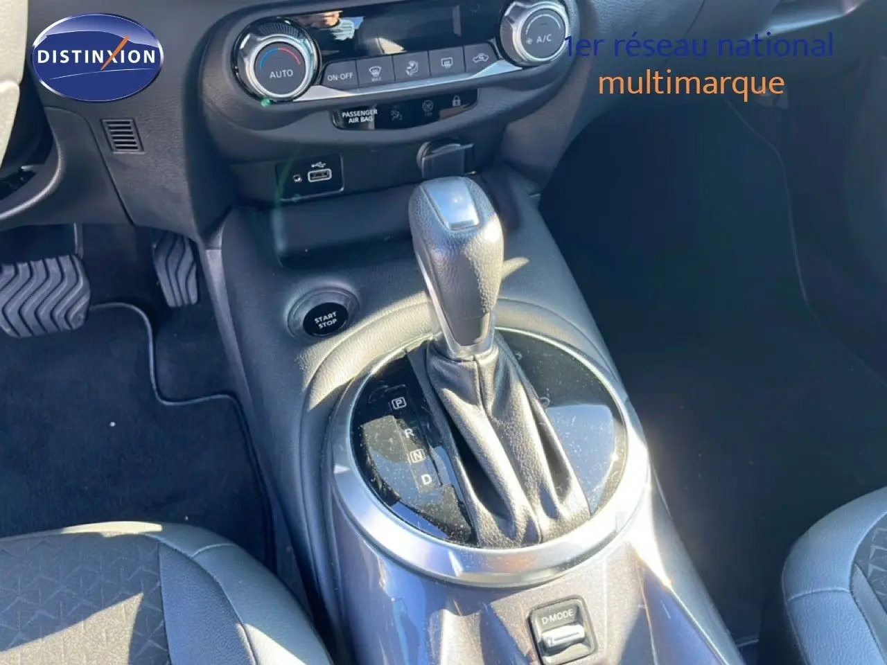 Gros plan sur la console centrale et levier de vitesse de la Nissan Juke Hybrid 2024 en gris squale métal, intérieur noir.