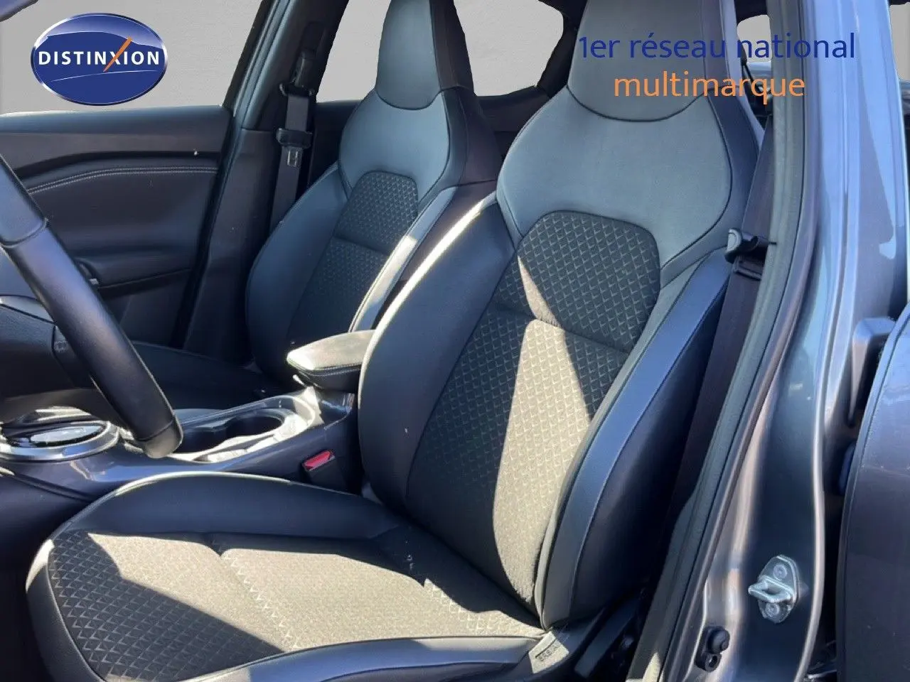 Vue intérieure côté conducteur du Nissan Juke Hybrid 2024, sièges en cuir noir et tissu gris, porte ouverte.