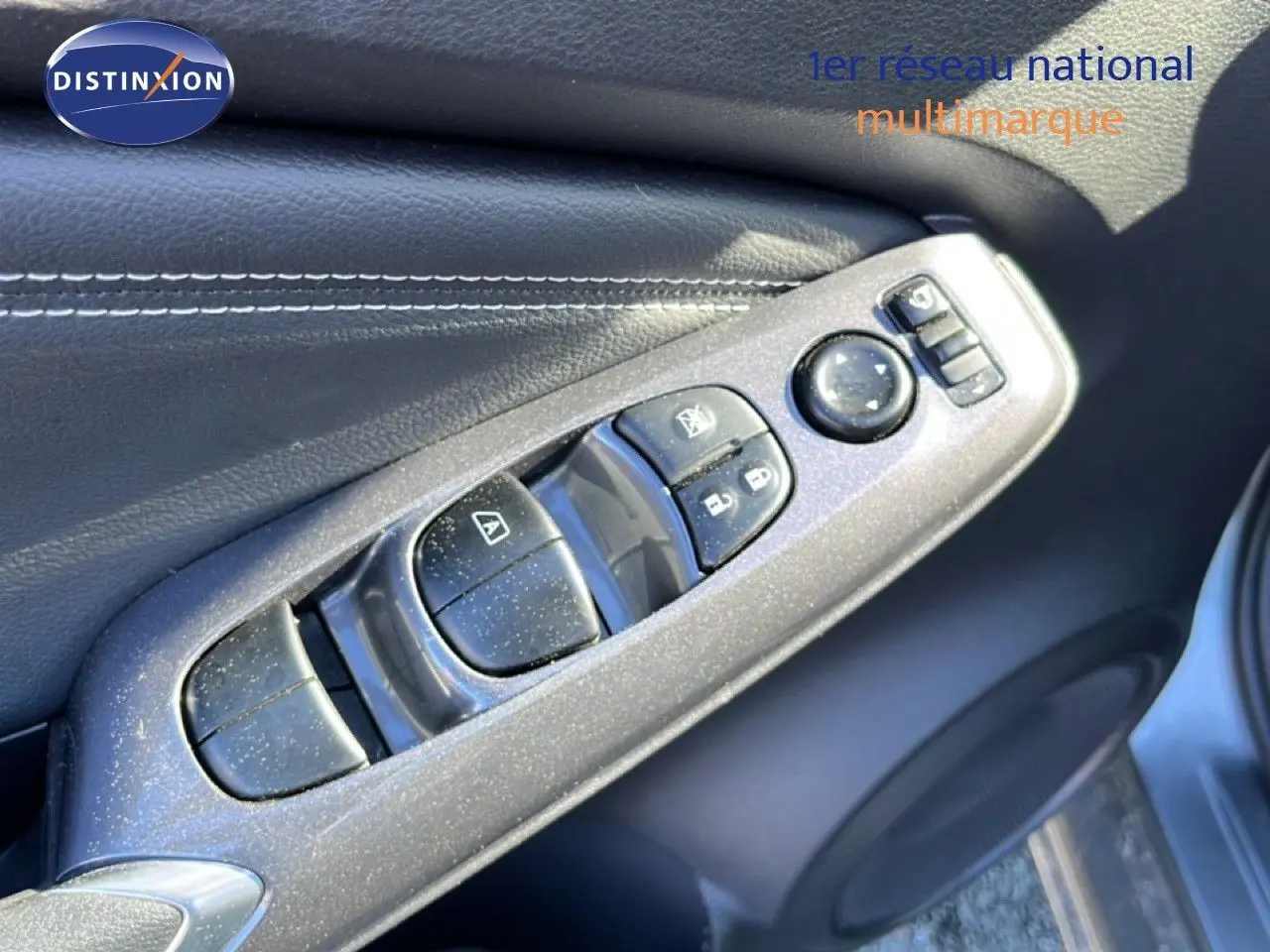 Gros plan sur les commandes de lève-vitres et rétroviseurs côté gauche d’un Nissan Juke gris squale métal 2024.