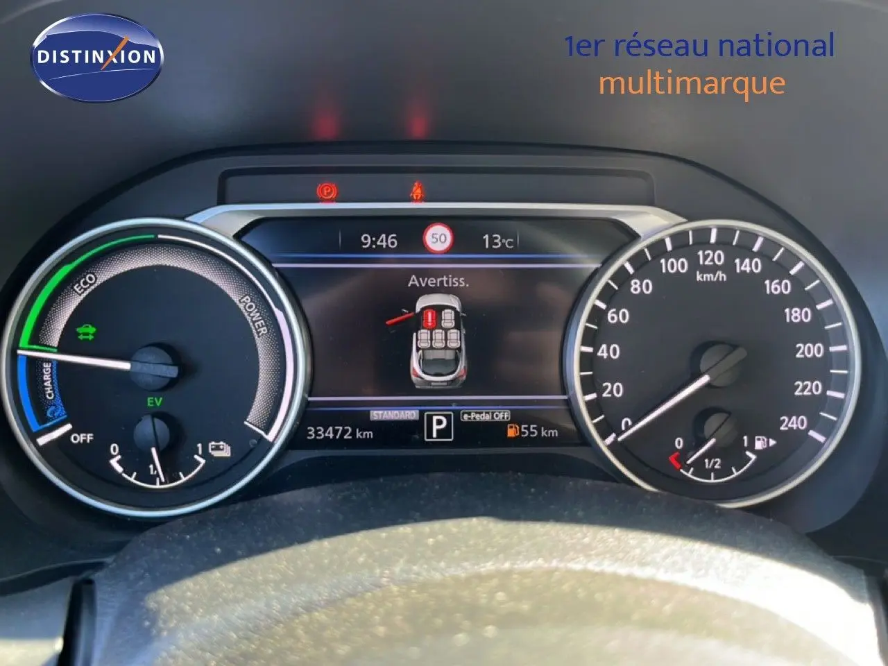 Tableau de bord du Nissan Juke Hybrid 2024 en gris, affichant compteurs et écran digital avec alertes et vitesse.