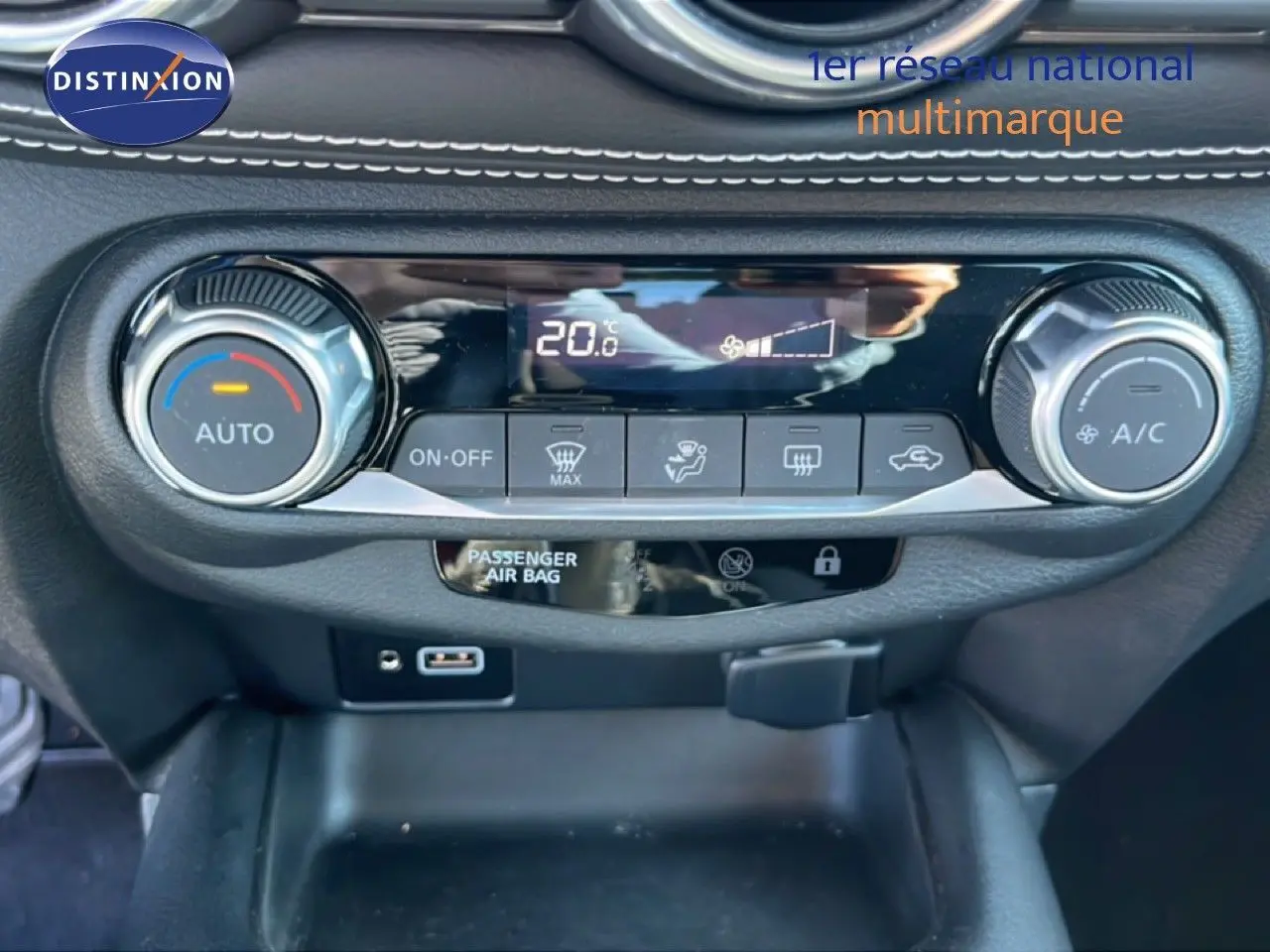 Détail de la console centrale du Nissan Juke 2024 gris, montrant les commandes de climatisation automatique et écran digital.