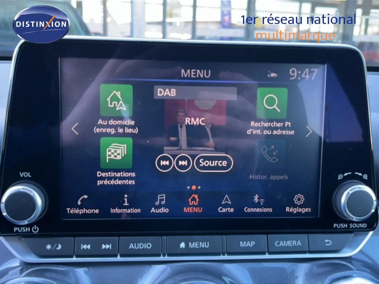 Écran tactile central du Nissan Juke Hybrid 2024, affichant le menu audio avec commandes autour, intérieur gris.