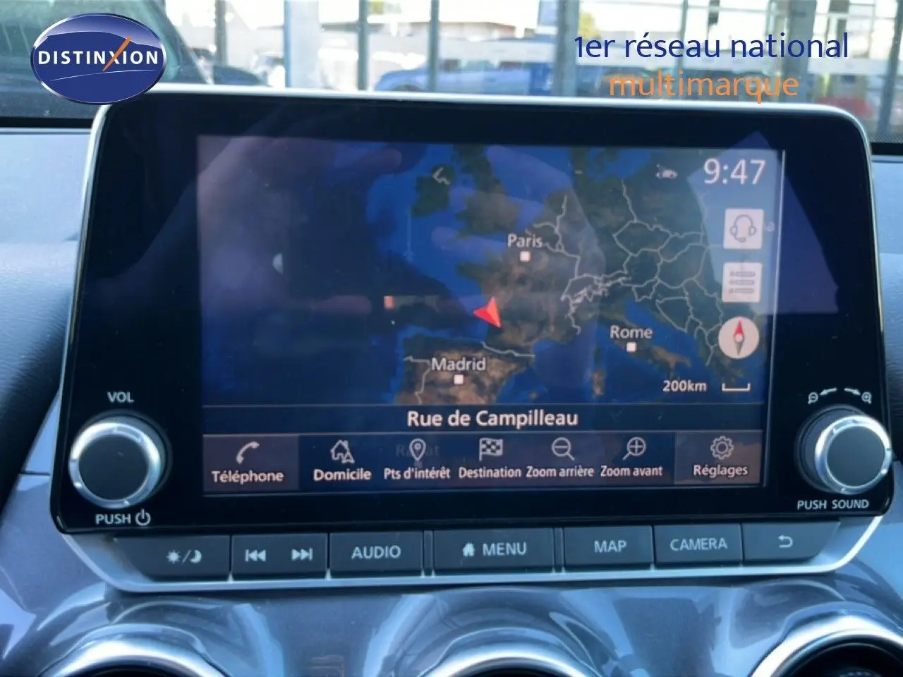 Vue intérieure du tableau de bord du Nissan Juke Hybrid 2024, écran tactile GPS affichant une carte de navigation.