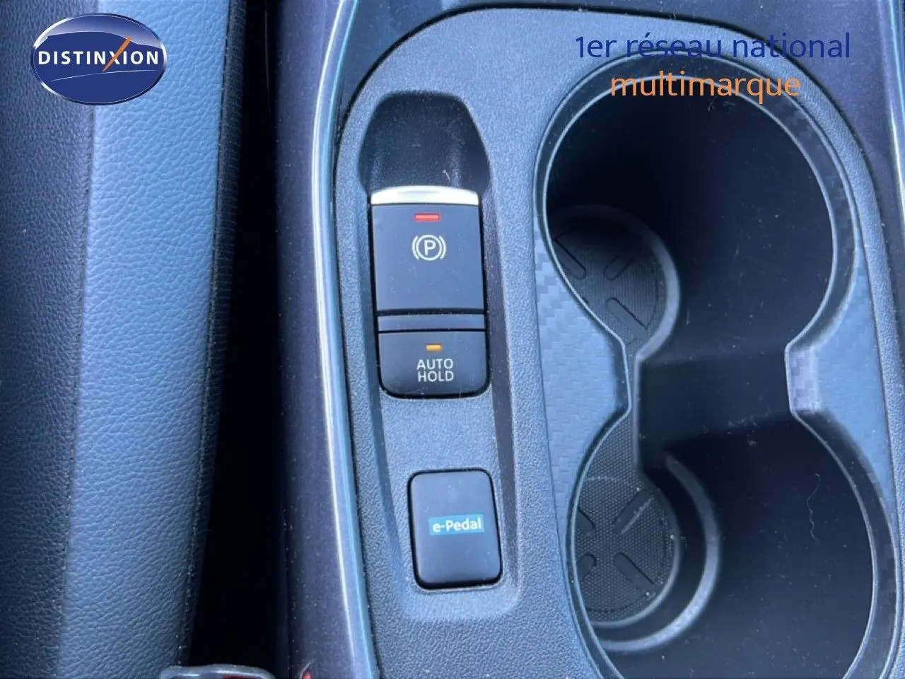 Vue rapprochée de la console centrale noire du Nissan Juke Hybrid 2024 avec boutons de frein à main, auto hold et e-Pedal.