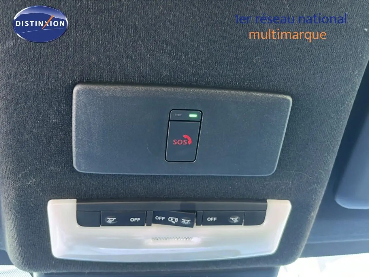 Vue intérieure du plafond du Nissan Juke Hybrid 2024 gris, montrant les commandes d’éclairage et le bouton SOS.
