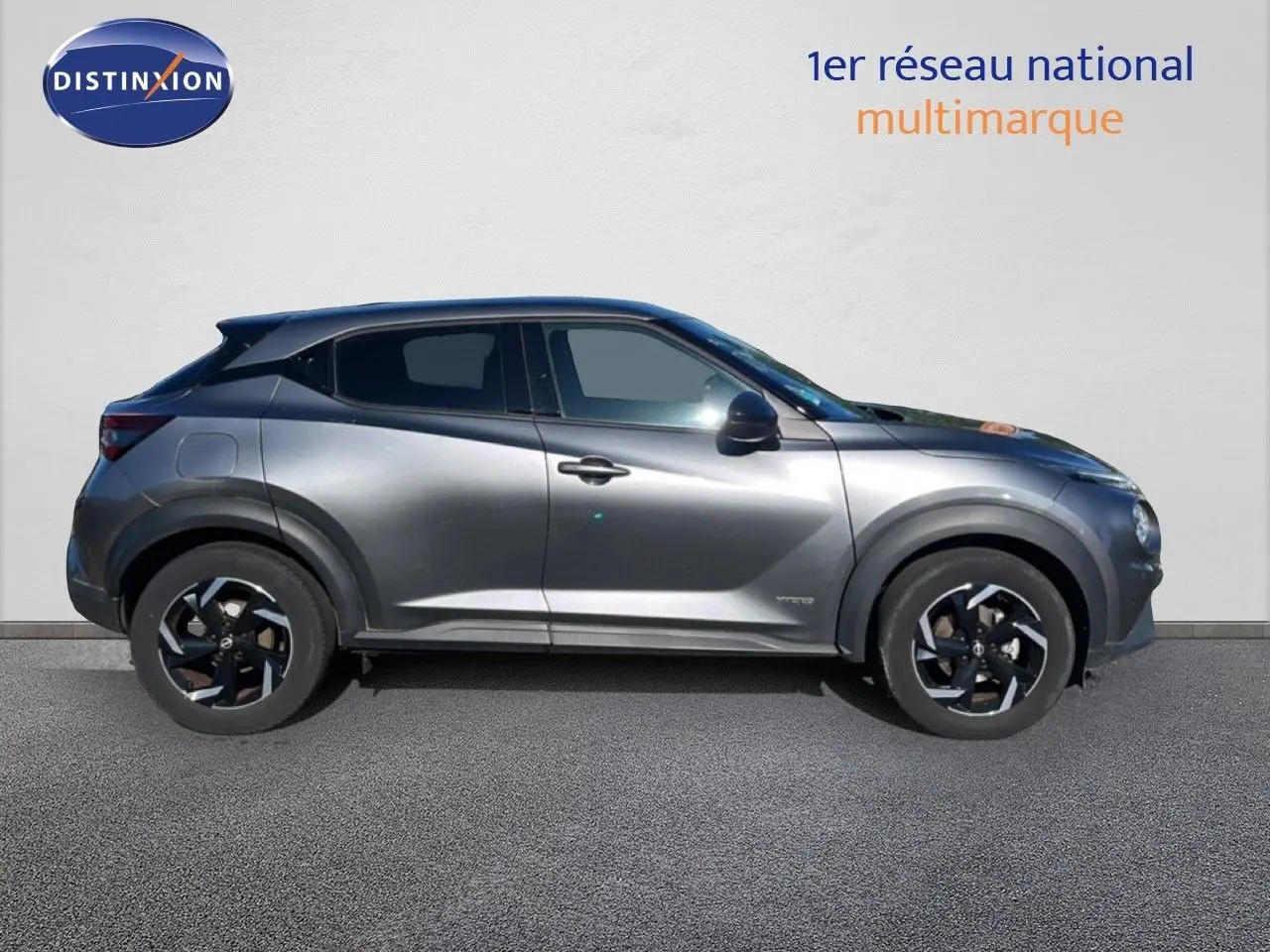 Profil droit du Nissan Juke Hybrid 143ch Business+ 2024 en gris squale metal avec jantes noires bicolores.