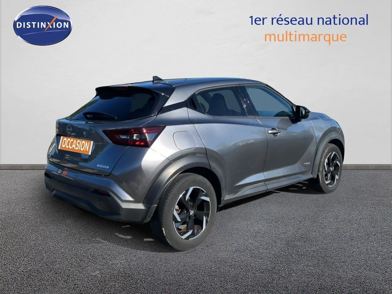 Nissan Juke Hybrid gris squale métal vu en 3/4 arrière droit, soulignant ses lignes modernes et ses jantes bi-ton.