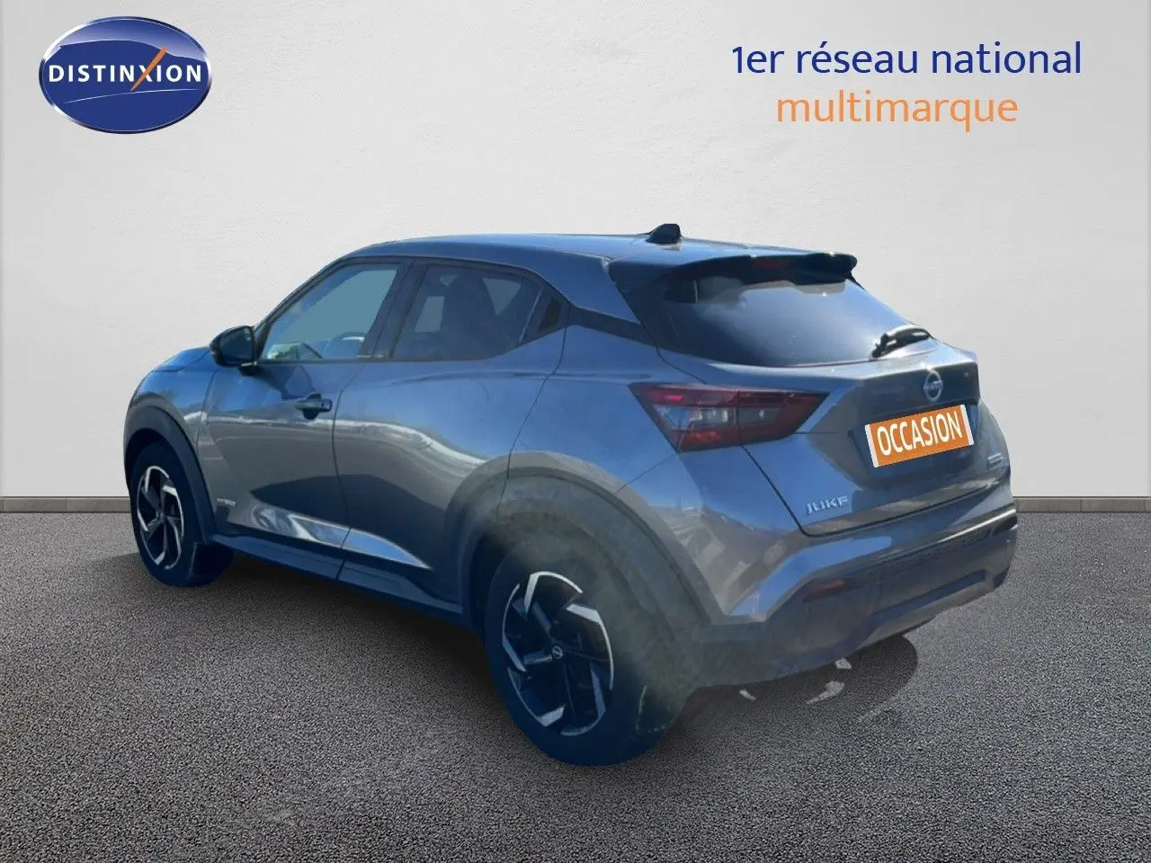 Vue 3/4 arrière droite d'un Nissan Juke hybride gris squale métal avec jantes noires et toit foncé.