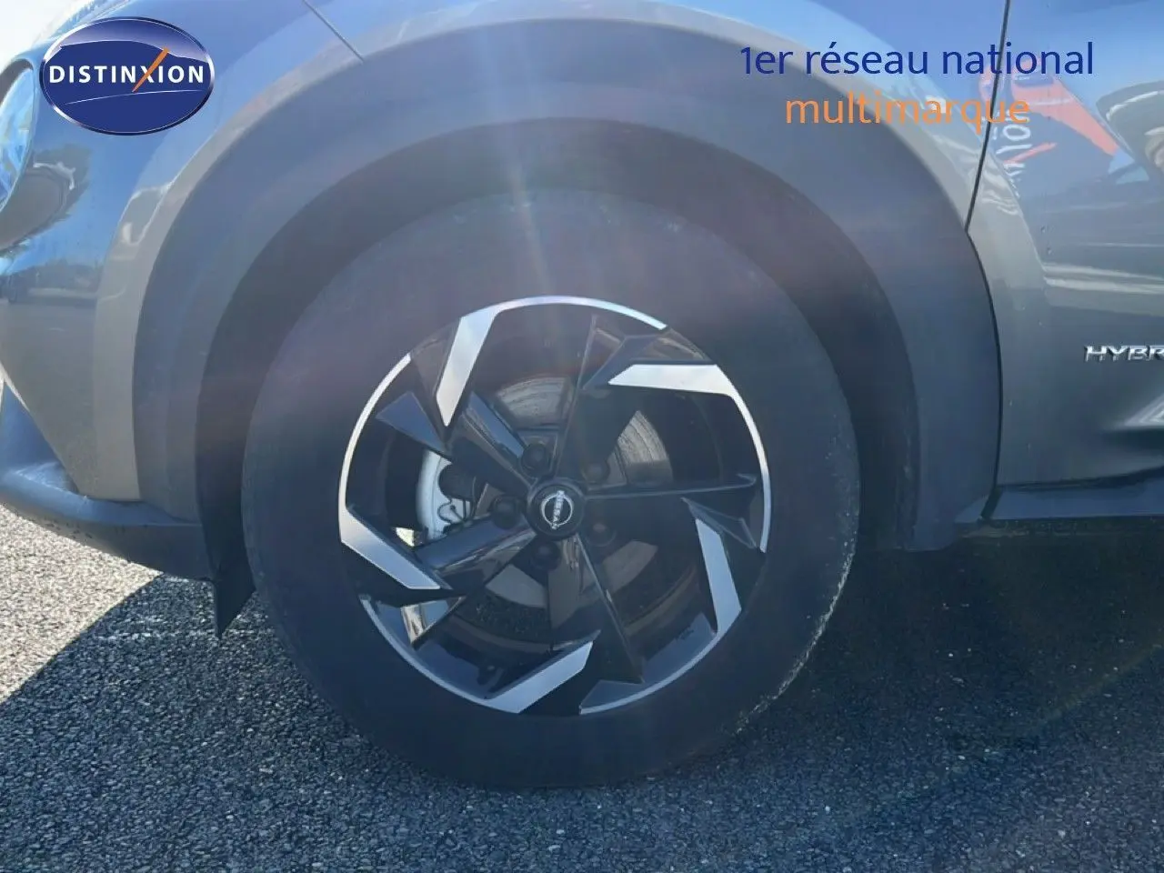 Gros plan sur la roue avant gauche du Nissan Juke gris squale métal, avec jante noire et argentée au design moderne.
