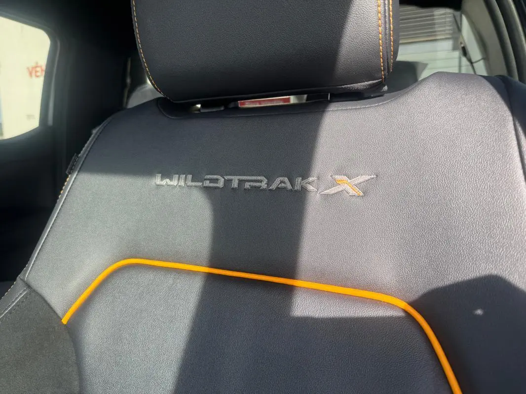 Détail du siège avant en cuir noir avec surpiqûres orange et logo Wildtrak X brodé.