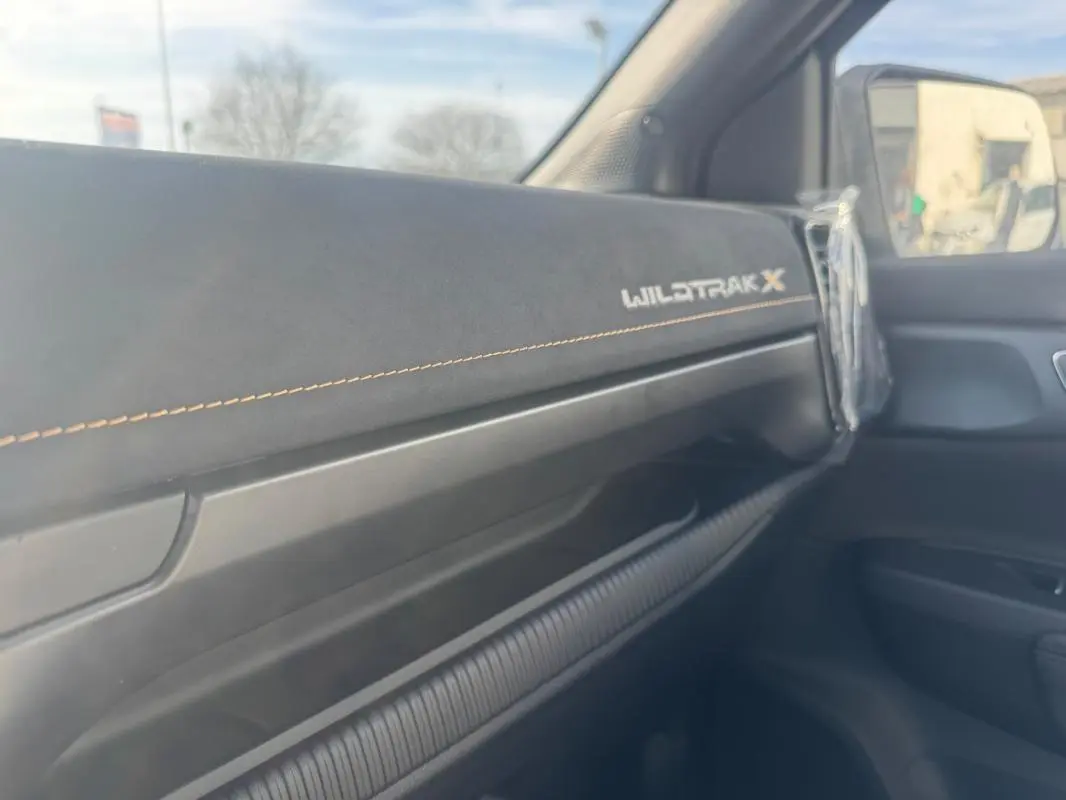 Détail intérieur côté passager du Ford Ranger Wildtrak X 2025 avec tableau de bord noir et surpiqûres orange.