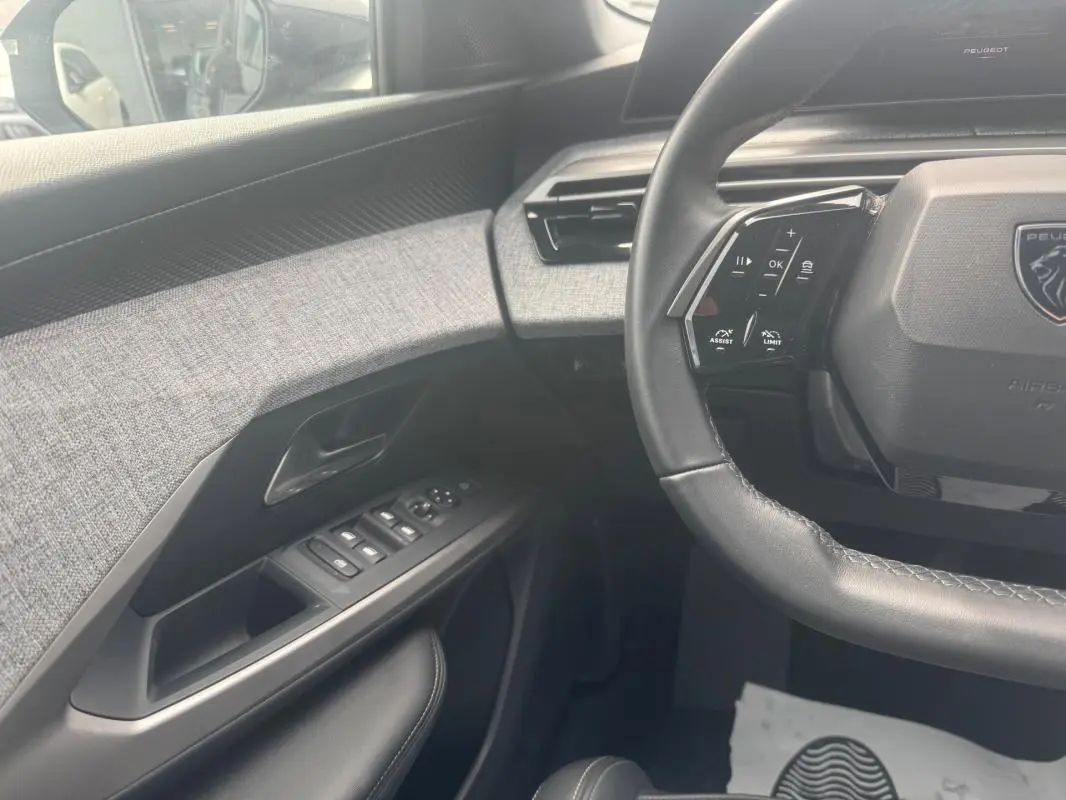 Vue intérieure côté conducteur du Peugeot 5008 noir, mettant en valeur la porte avec commandes électriques et le volant multifonction.
