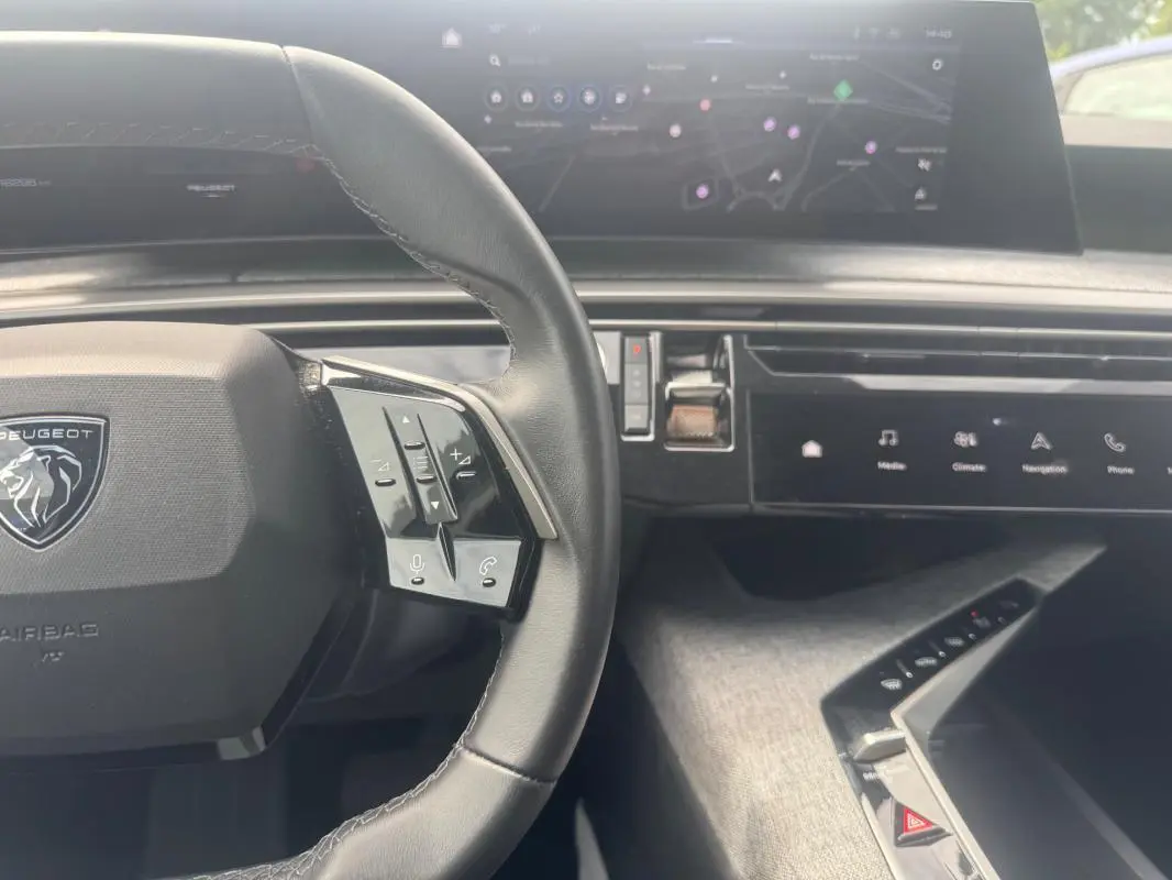Vue intérieure centrée sur le volant cuir noir et le cockpit numérique du Peugeot 5008 Hybrid 2025.