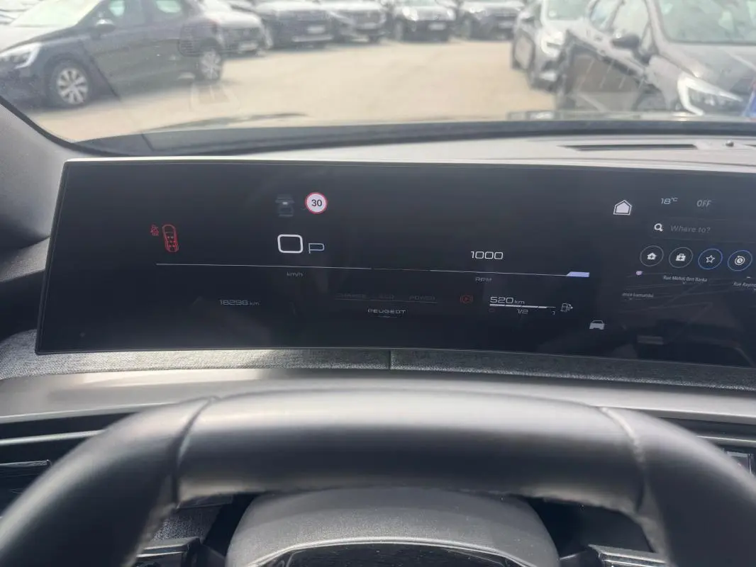 Vue intérieure du cockpit numérique du Peugeot 5008 Hybrid noir, affichant la vitesse, la consommation et la navigation.