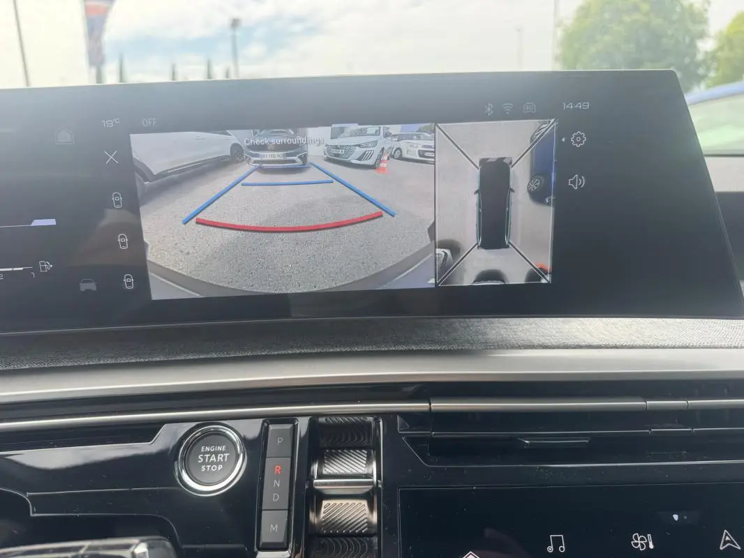 Vue intérieure du tableau de bord du Peugeot 5008 Hybrid 2025, écran affichant la caméra de recul et l'aide au stationnement.